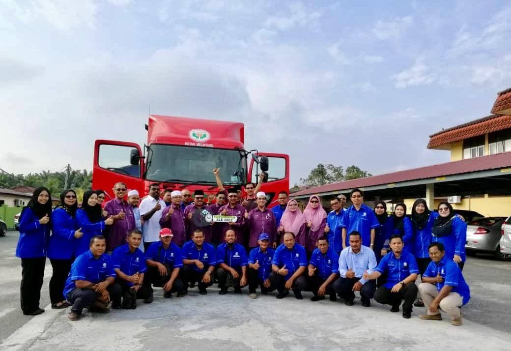 Khairuddin (berdiri, lapan dari kiri) memegang replika kunci treler sambil bergambar bersama pengurusan PPK Hutan Melintang.