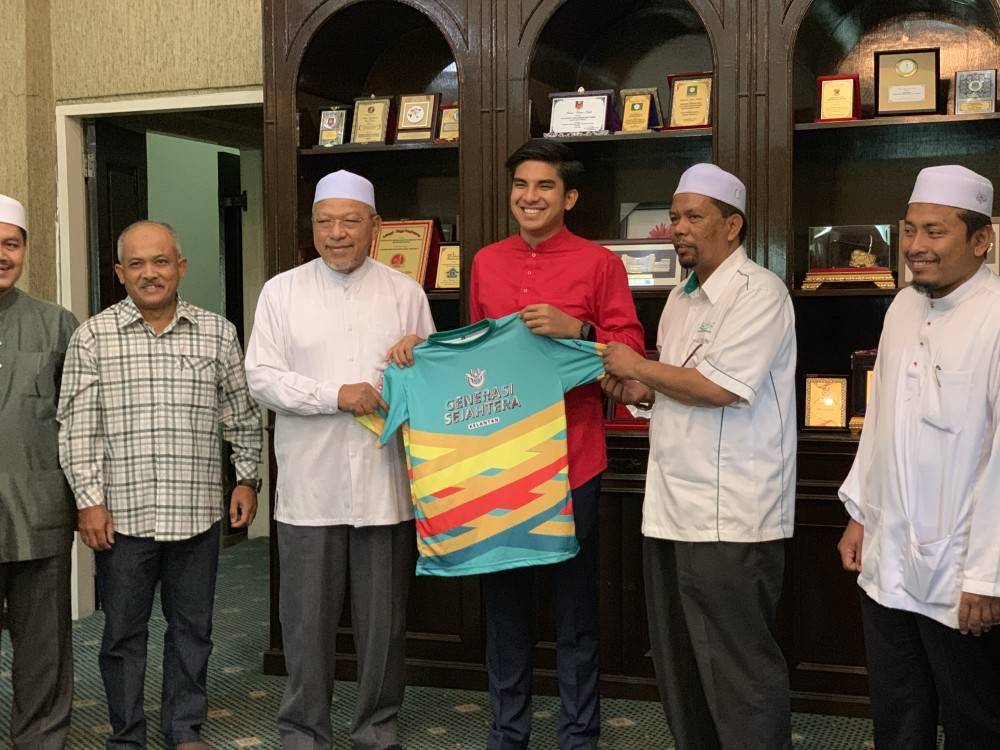 Syed Saddiq (tiga kanan) menerima jersi daripada Ahmad ketika kunjungan hormat, Jumaat lalu.