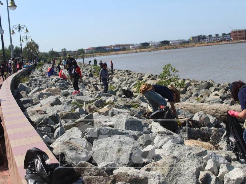 Sukarelawan sedang membersihkan kawasan pesisir pantai.