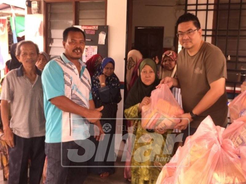 Tuan Peng (kanan) menyampaikan sumbangan berupaya barangan keperluan harian kepada salah seorang penduduk Kampung Melayu Pandan yang terjejas akibat banjir kilat baru-baru ini.