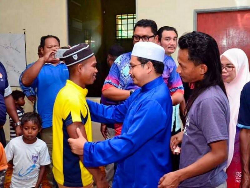 Anggota Dewan Undangan Negeri Paloh Amran Arifin (tengah) bersama remaja Orang Asli Ayub Raju, 23, yang memeluk Islam pada Program Seperlu Bersama Orang Asli di Pusat Daerah Mengundi (PDM) Kampung Pasir Linggi, Pos Lebir hari ini. - Foto Bernama