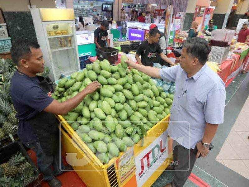 Mohd Idris (kiri) melayan pelanggan pada JTDL di Kuantan Parade.