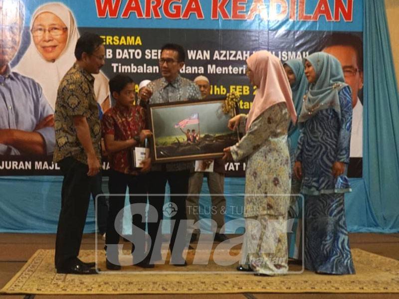 Wan Azizah menandatangani hasil karya Abdullah Dean sempena majlis temu mesra warga PKR Terengganu bersama TPM, hari ini.