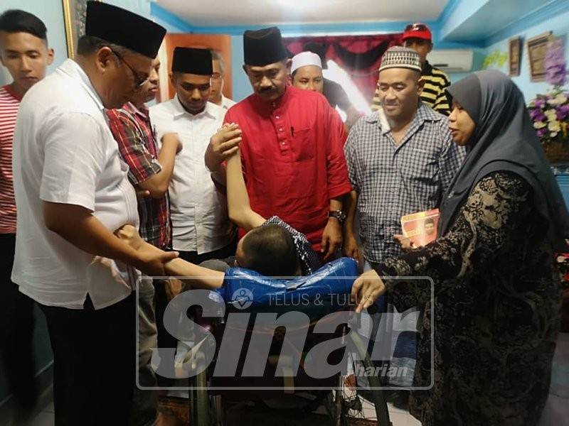 Abu Bakar (kanan) dan Muhammad Aiman (kiri) beramah mesra dengan Mohd. Bukhari yang cacat sejak lahir semasa program ziarah di Kampung Batu 3, Semenyih hari ini.