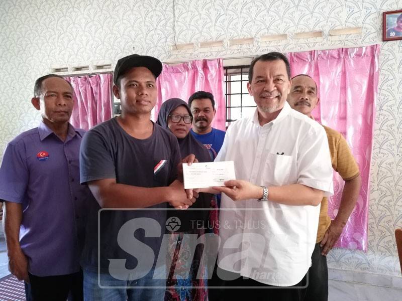 Muhammad Nur Faris menerima cek bernilai RM1,000 daripada Solihan. 