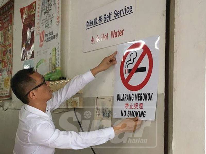 Chee Leong melekatkan papan tanda larangan merokok di sebuah premis makanan yang gagal mempamerkan tanda larangan merokok.