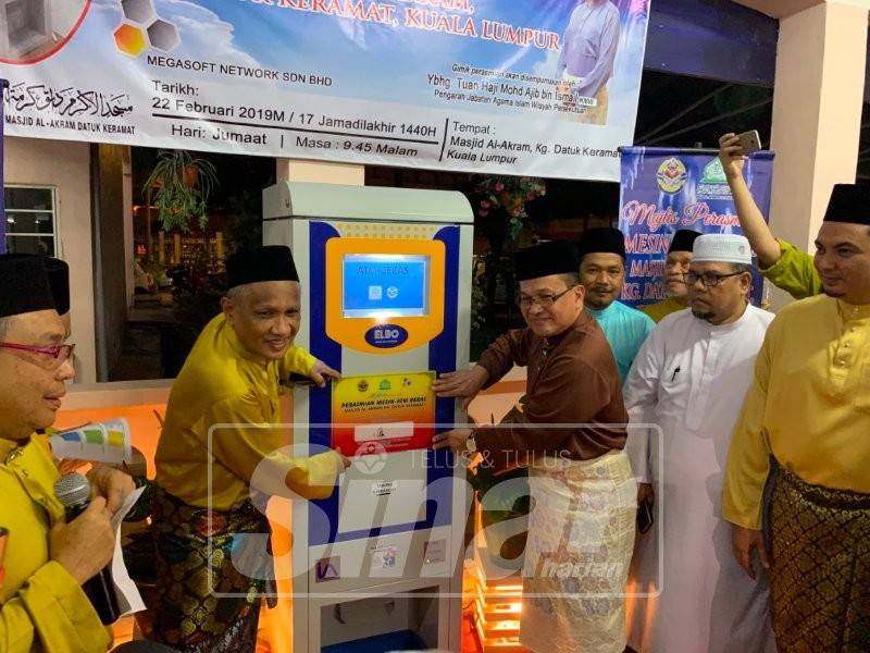 Mohd Ajib (kanan) ketika merasmikan mesin ATM beras di Masjid Al-Akram.