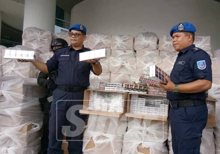 Mohd Khairuddin (kiri) menunjukkan sebahagian rokok yang dirampas.