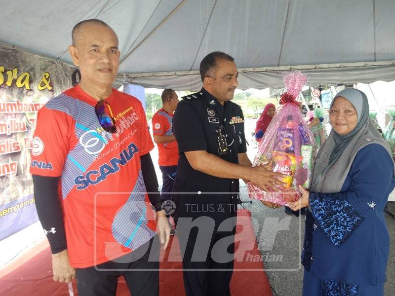 Mohd Taufik menyampaikan hamper kepada salah seorang ibu tunggal sambil diiringi Che Ibrahim (kiri).