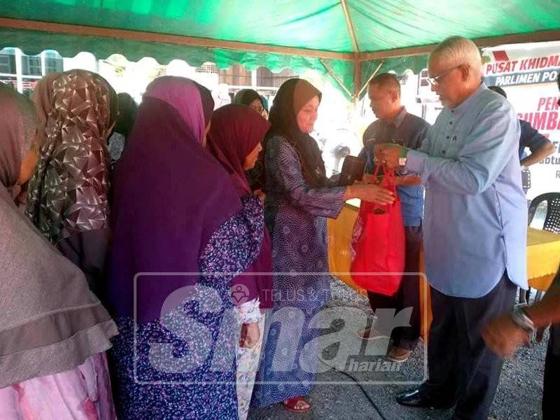 Mahfuz (kanan) ketika menyerahkan sumbangan kepada penerima sempena program jejak asnaf dan penyerahan dana khas DUN Derga.