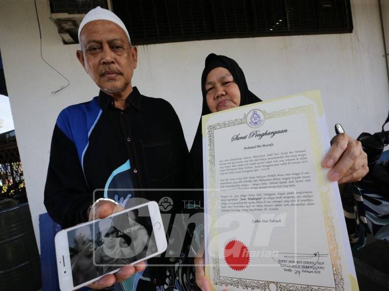 Mohd Mustafa menunjukkan gambar arwah yang sentiasa dalam ingatan dan ibu Allahyarham, Masitah Awang menunjukkan sijil penghargaan oleh Ketua Polis Terengganu kepada arwah.