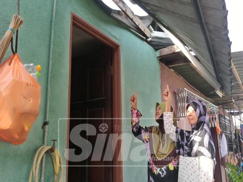 Siti Rohani (kanan) bersama Salmi menunjukkan bumbung rumah yang diterbangkan angin.