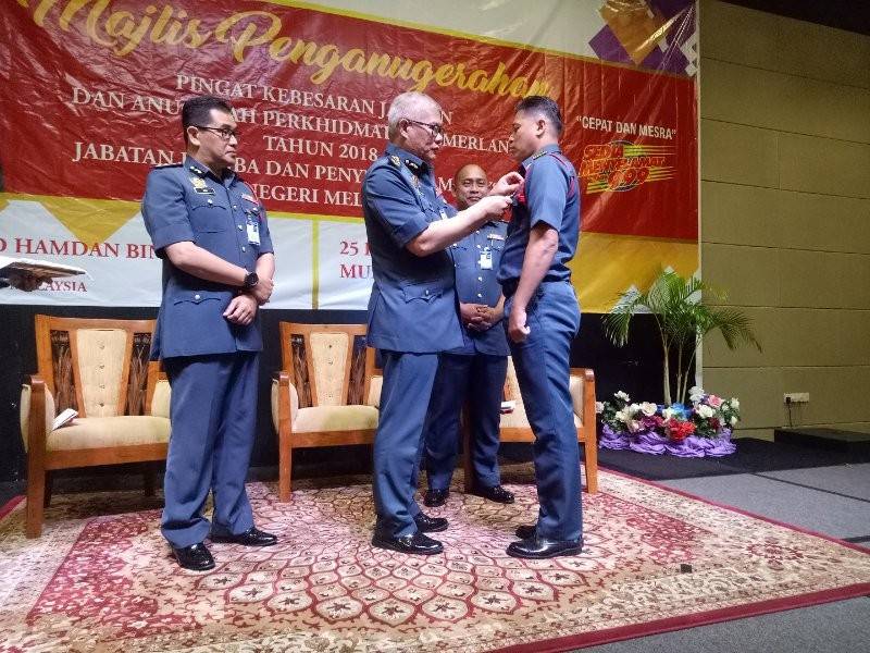 Mohammad Hamdan memakaikan pingat kepada salah seorang pegawai pada majlis itu.