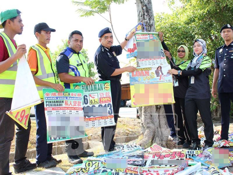 Noorzainy (empat, kiri) menurunkan salah satu poster ah long yang dilekatkan di pokok.