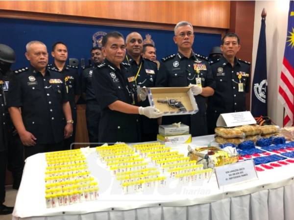 Hasanuddin (dua, kanan) bersama Ketua Polis Daerah Kota Bharu, Asisten Komisioner Abdul Rahim Daud menunjukkan pistol yang dirampas daripada suspek.