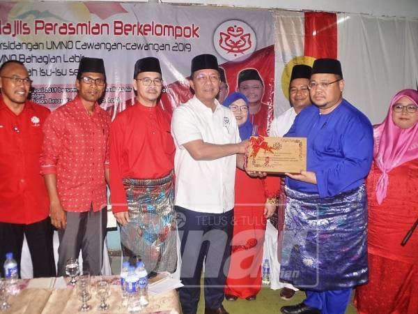 Hasni (empat, kiri) menerima cenderamata selepas menyempurnakan majlis perasmian berkelompok Persidangan Cawangan UMNO Bahagian Labis di Kampung Usaha Jaya.