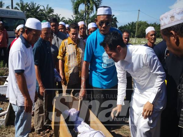 Aliff Syukri menatap jenazah bapanya yang dikebumikan di Tanah Perkuburan Islam Kampung Sungai Nibong, di sini, pagi tadi.