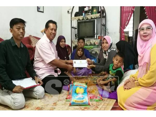 Zulkepli (dua, kiri) menyampaikan zakat dari Yayasan Amal Datuk Zul Wisma kepada Hatikah di rumahnya di Kampung Banggol Gajah Mati.