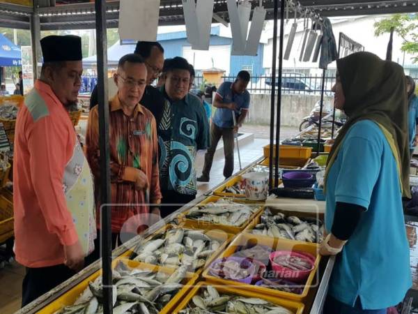 Fauzi (dua, kiri) mengiringi Zulkifli (tiga, kiri) melihat hasil laut yang dijual pada Program Jualan MBB di My Farm Outlet, Chendering hari ini.