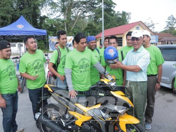 Shahiruddin menyerahkan topi keledar kepada peserta kembara sebagai simbolik program berkenaan.