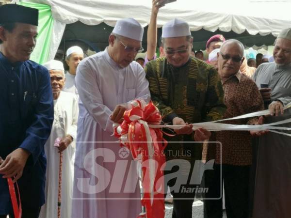 Ahmad (dua, kiri) memotong reben sebagai tanda perasmian Madrasah Haji Ibrahim, Kampung Jalan Bunut Susu.