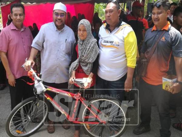 Mujahid (tengah) menyerahkan hadiah utama cabutan bertuah berupa sebuah basikal kepada pengunjung terpilih sewaktu merasmikan program Karnival Rahmah dan Ramah di Sungai Betul Bawah, Parit Buntar hari ini.