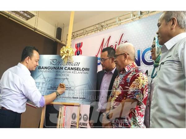 Dr Maszlee (kiri) menandatangani plak perasmian Bangunan Canselori UMK petang tadi.