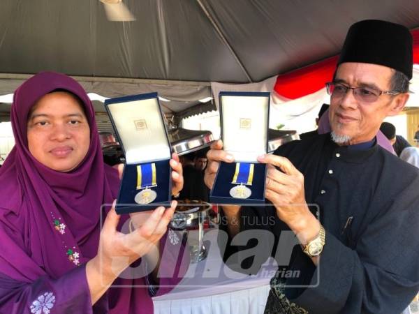 Wan Kamilah Yaacob, 54 (kiri) dan Wan Ibrahim Mat Daud, 61 menunjukkan pingat yang diterima bagi pihak allahyarham anak mereka.