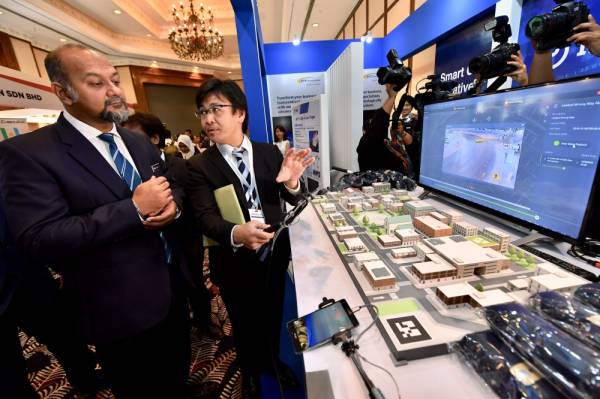 Gobind Singh Deo diberi penerangan oleh Shogo Nakamura dari NTT berkenaan inisiatif Bandar Pintar semasa melawat pameran selepas merasmikan dan melancarkan Cyberjaya Infra Conference and Exhibition 2019 hari ini. -Foto Bernama