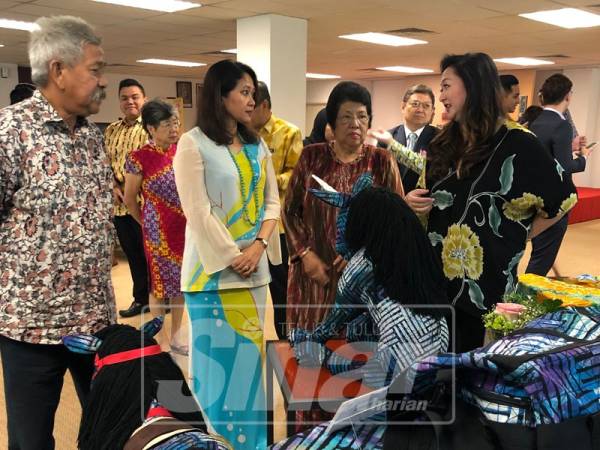 Suryani (dua, kiri) mendengar penerangan daripada Pengerusi Yayasan Budi Penyayang Malaysia, Nori Abdullah (kanan) mengenai pameran hasil batik yang menjadi juara pada Piala Seri Endon tahun lalu.