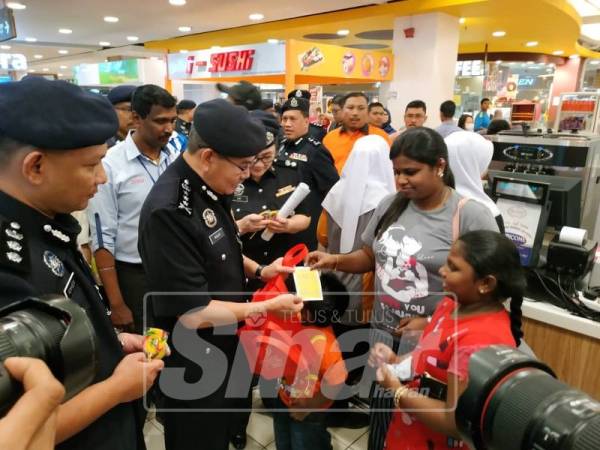 Mazlan (kiri) beramah mesra dengan orang ramai semasa Program High Profile Policing.