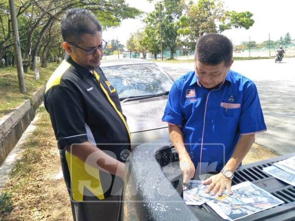 Chon Siang (kanan) menerangkan sesuatu mengenai cadangan persimpangan jalan Semambu bagi kurangkan kesesakan kepada wakil Jabatan Kerja Raya.
