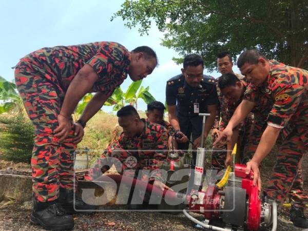 Khairul (tengah) melihat pengujian pam wajax yang dikendalikan anggota Balai Bomba Bukit Gambir, Tangkak.
