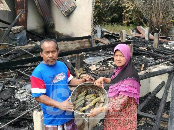 Faridah dan suami, Wan Omar menunjukkan kuih tepung bungkus yang selamat dari kebakaran sehingga memusnahkan rumah mereka.