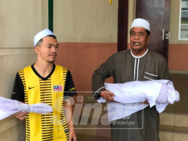 Meor Ikram (kiri) mengiringi jenazah anaknya untuk dibawa pulang dan dikebumikan di Tanah Perkuburan Changkat Larang, hari ini.