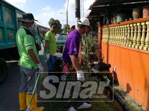 Sukarelawan membersihkan kawasan longkang di sekitar Jalan Nenas, Taman Kota Masai, hari ini.