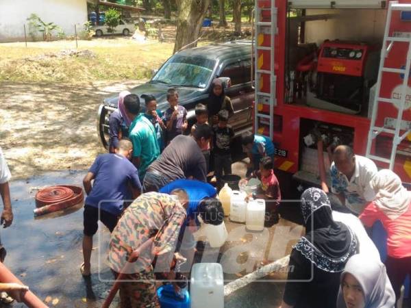 Anggota bomba membantu mengisi air ke dalam bekas dibawa penduduk.