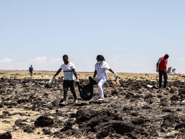 Pekerja penyelamat mengangkat mayat di lokasi pesawat Ethiopia Airlines terhempas pagi semalam, berhampiran bandar Bishoftu. - FOTO AFP