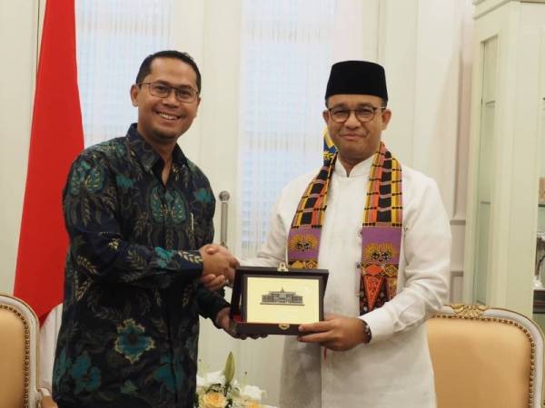 Mohd Asmirul (kiri) ketika menerima cenderahati daripada Anies Baswedan selepas tamat pertemuan itu.