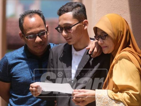 Ahmad Shahir Safwan (tengah) bersama ibu dan bapanya, Salwanu Ambak dan Ahmad Sabri Omar melihat keputusan SPM yang diperoleh hari ini.