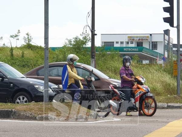 Penunggang motosikal menggunakan topeng muka.