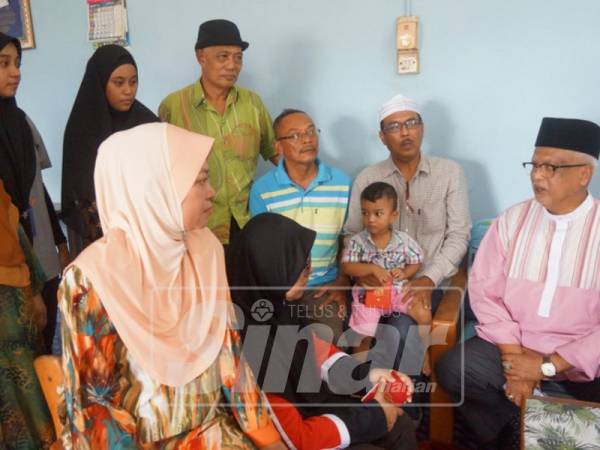 Mahfuz (kanan) berbual dengan ahli keluarga Tarmizi di rumah mereka di Hutan Kampung.