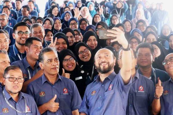 Mukhriz (tiga, kanan) berswafoto bersama sebahagian warga Keda, seusai perhimpunan bulanan di pekarangan pejabat Keda, di Jalan Langgar.