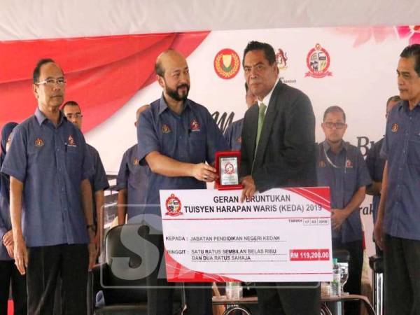 Mukhriz (dua, kiri) menyerahkan replika cek geran peruntukan Tuisyen Harapan Waris (Keda) kepada wakil Jabatan Pendidikan Negeri Kedah, disaksikan Muhd Kameh (kiri).