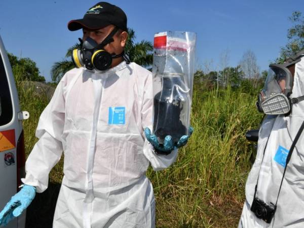 Petugas Jabatan Alam Sekitar mengambil sampel sisa bahan yang mencurigakan dari tong biru di bawah Jambatan Sungai Sembilang berdekatan loji kumbahaan Tanjung Puteri hari ini. - Foto Bernama