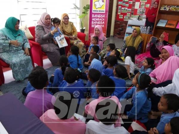 Shahaniza (tengah) dan Nafisah meluangkan masa membaca buku bersama kanak-kanak selepas Majlis Perasmian Perpustakaan Desa Kampung Lebu, semalam.