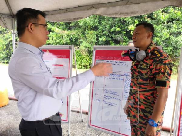 Hong Pin (kiri) mendengar taklimat dari pegawai bomba mengenai kejadian kebakaran di tapak pelupusan sampah Bandar Tenggara. 