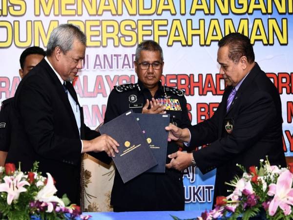 Mohamad Fuzi menyaksikan pertukaran MoU antara Pengerusi KPDRM, Datuk Seri Ayub Yaakob (kiri) dengan Presiden Persatuan Industri Keselamatan Malaysia, Datuk Seri Mustapa Ali (kanan). Foto Bernama