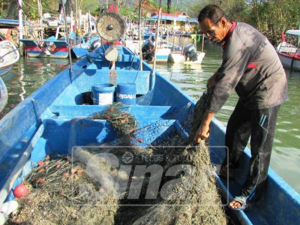 Nelayan pantai Teluk Bahang menunjukkan pukat yang rosak.