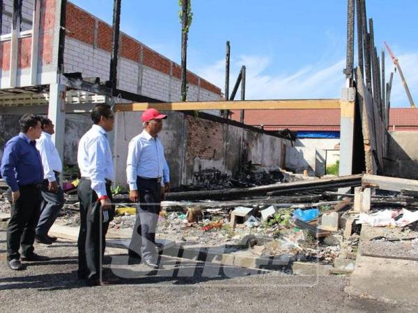 Mohd Zohdi (kanan) meninjau keadaan rumah kedai terbakar.